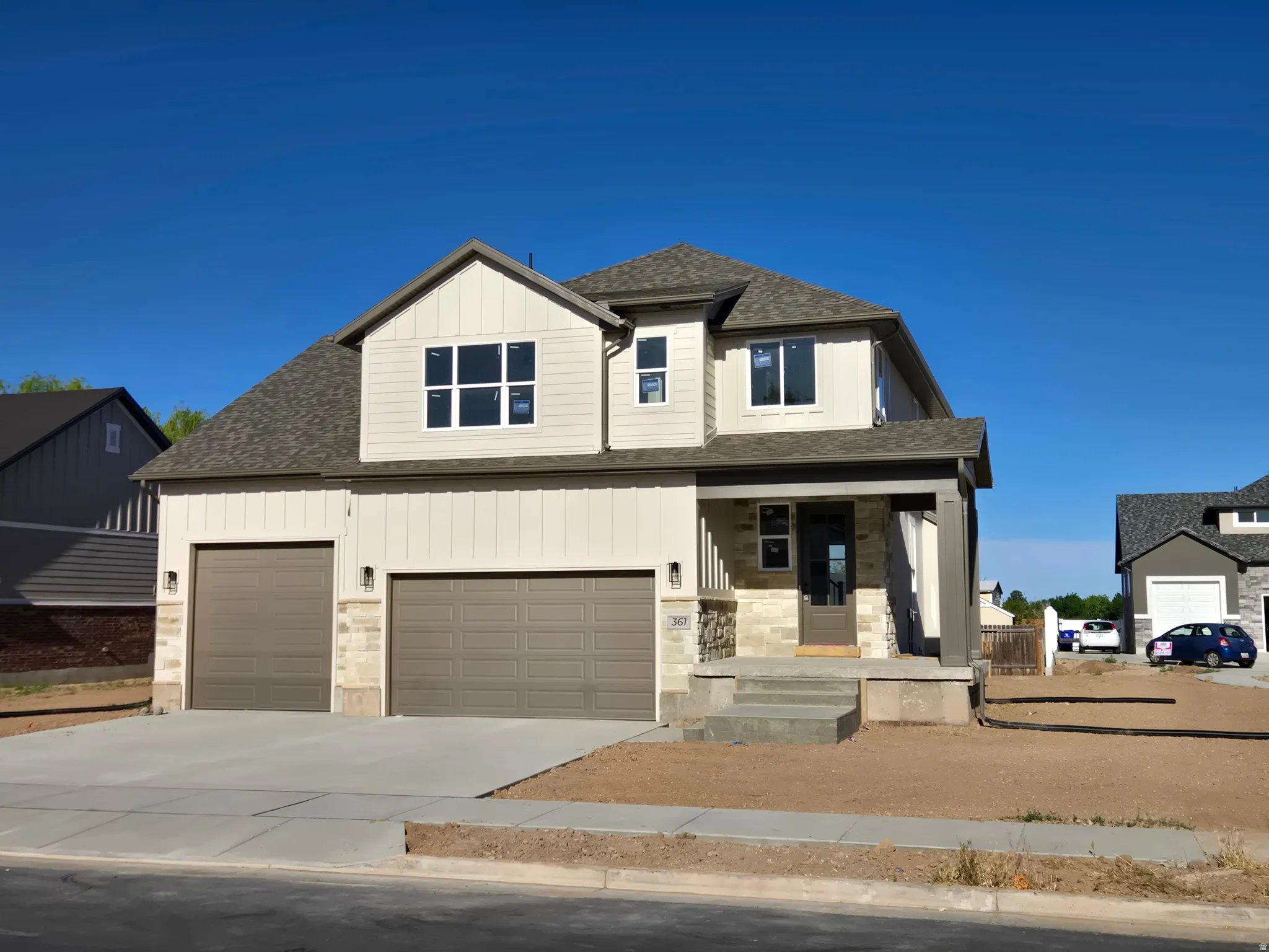 Two-story residence featuring a covered front porch, a two-car garage, and stone accent siding