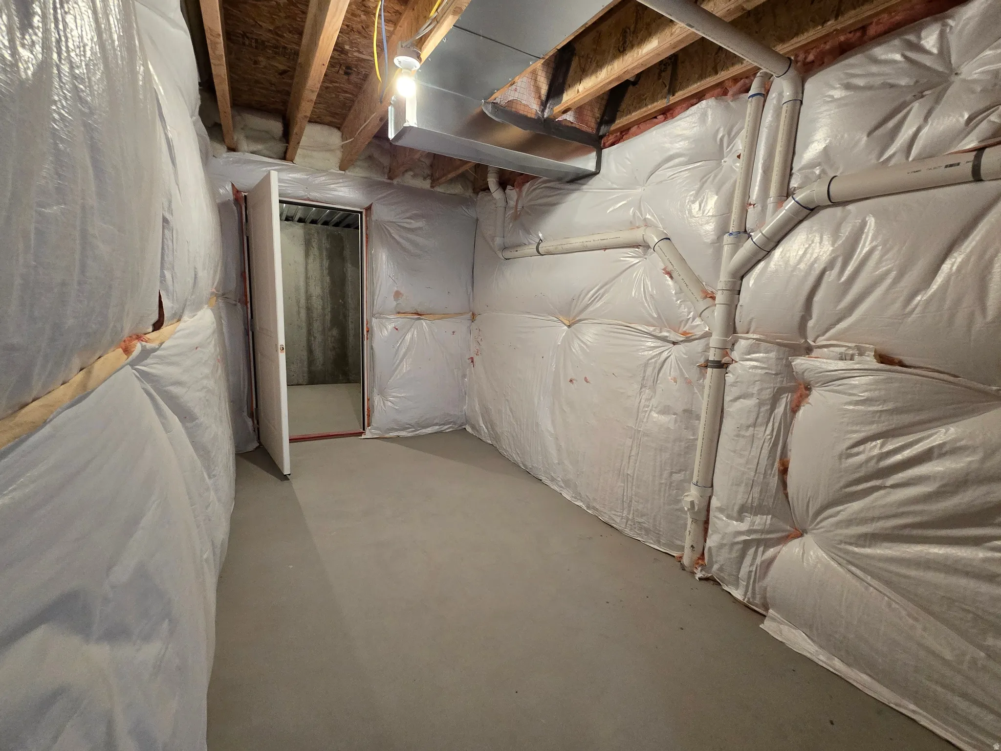 Unfinished basement with concrete flooring, exposed ceiling joists, and insulated walls