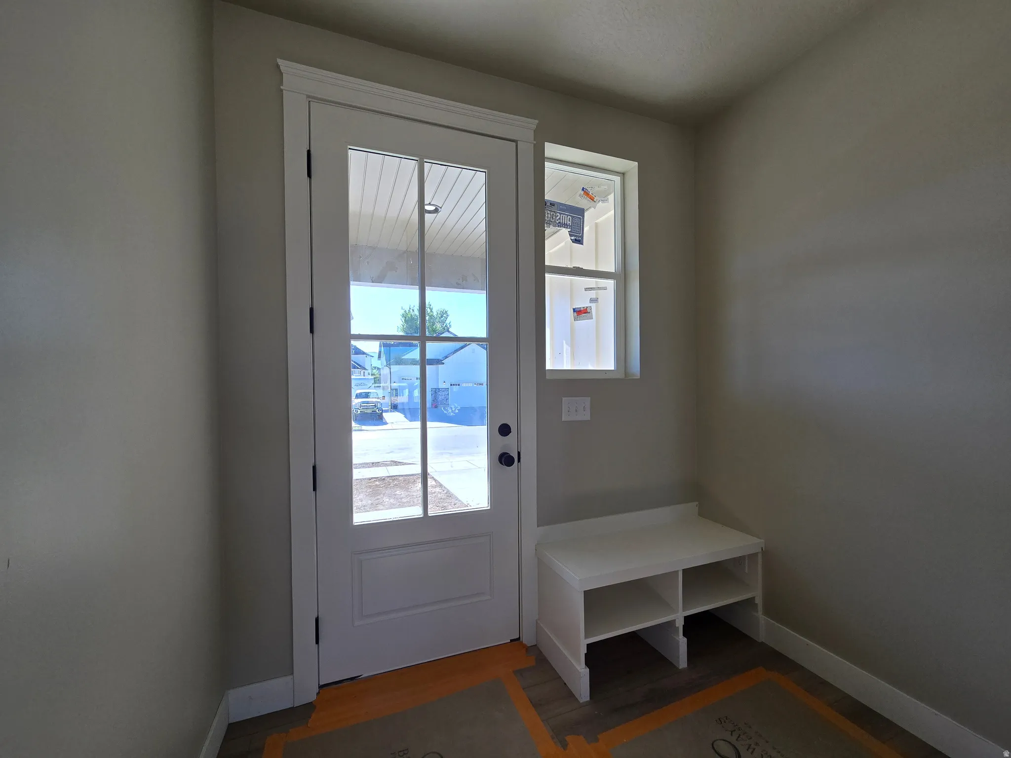 Entryway featuring a glass-paned door, a white storage bench, and wood-finish flooring