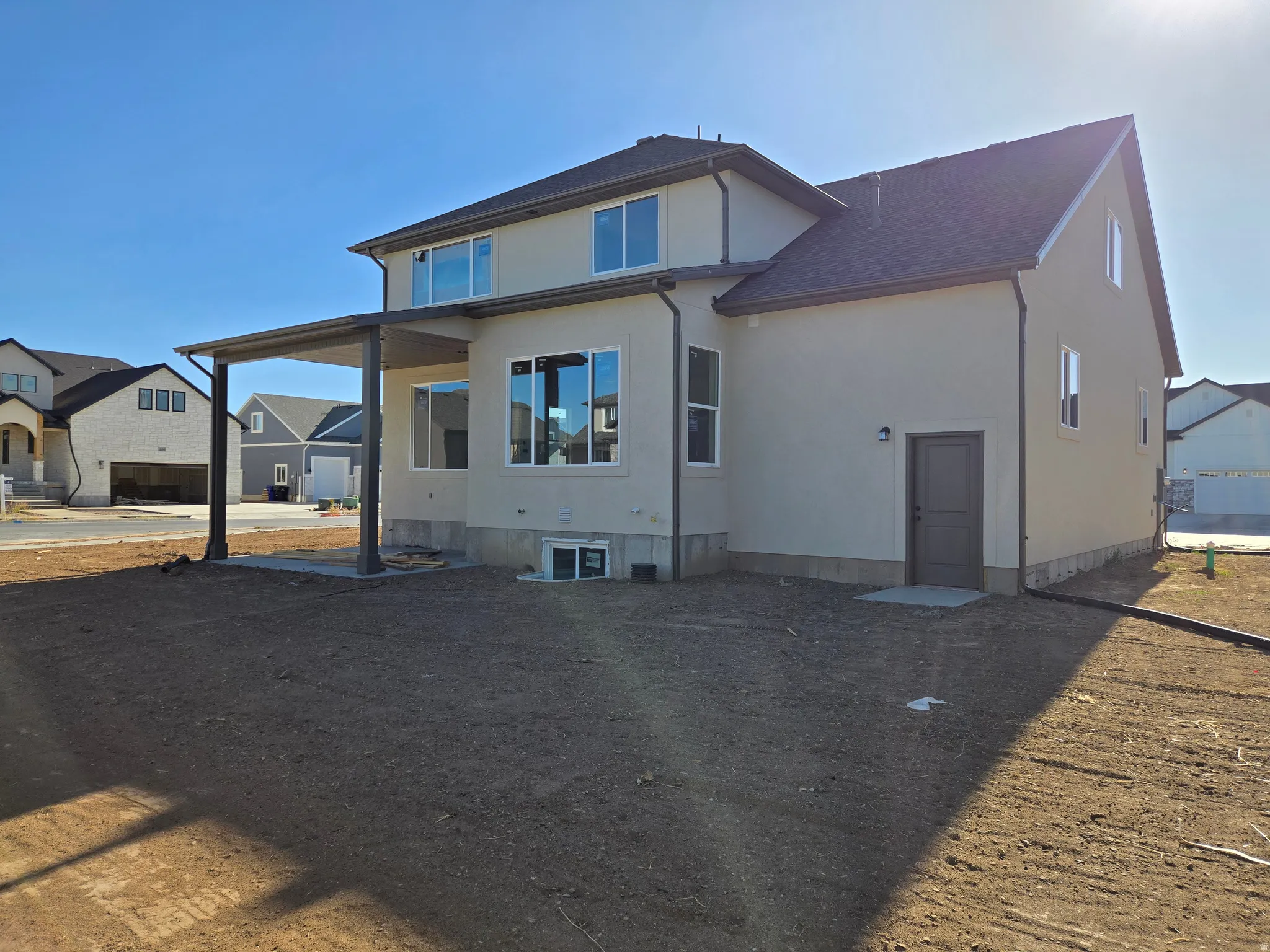 Contemporary home with light stucco exterior, dark trim windows, and a covered patio