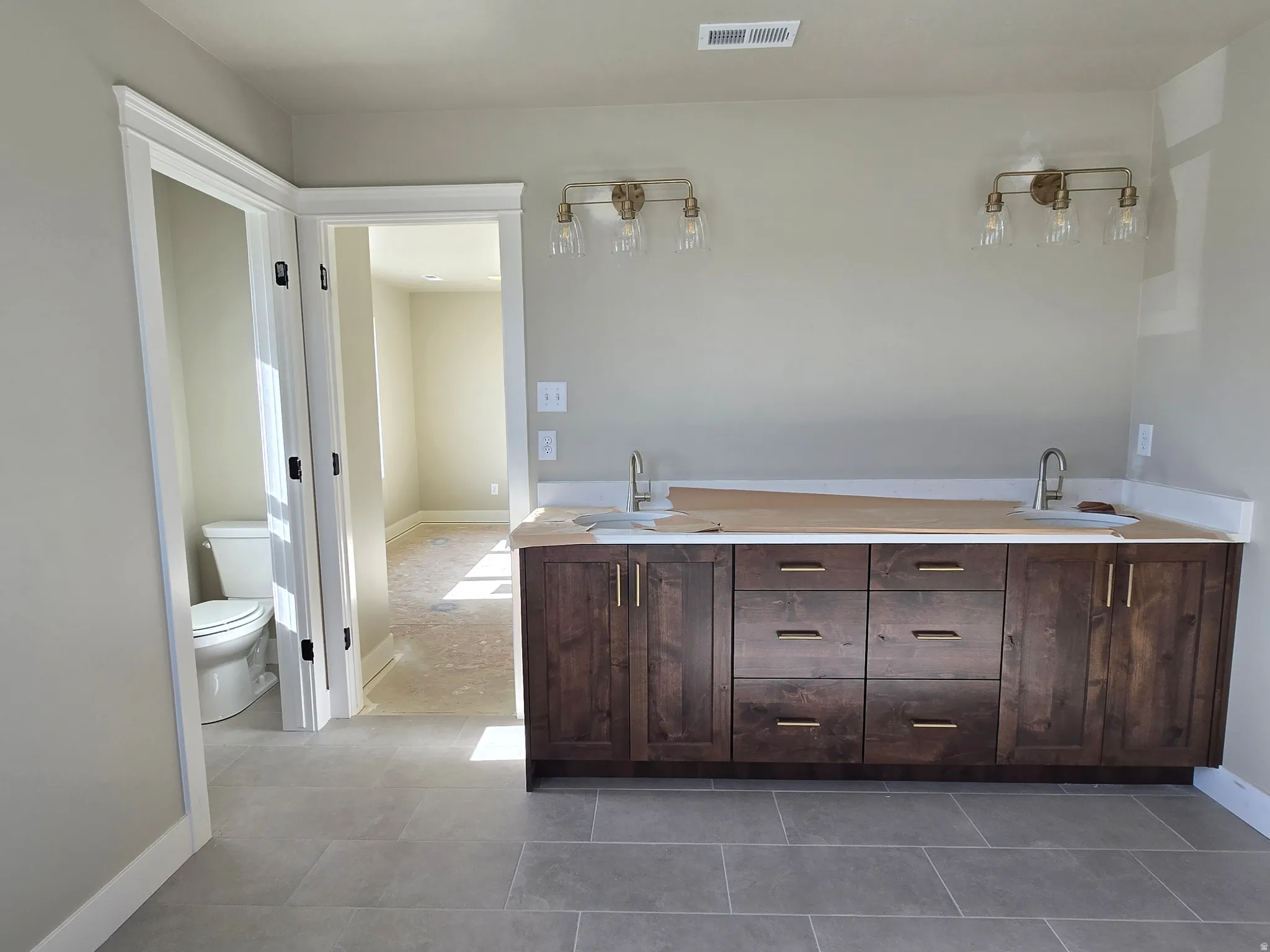 Dual vanity with rich wood-finish cabinetry, brushed brass hardware, and undermount sinks