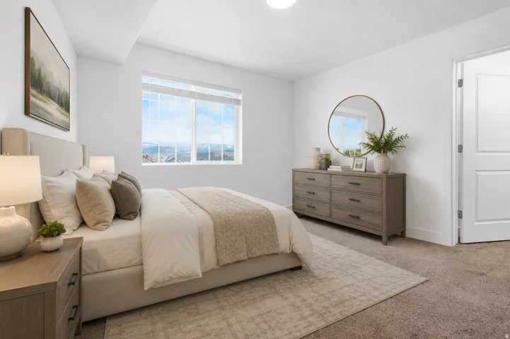 Spacious bedroom featuring light-toned walls, a large window, and soft carpet flooring