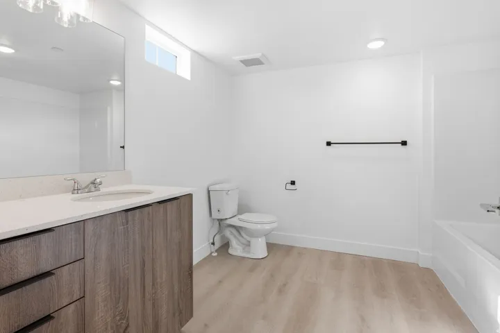 Bathroom featuring a wood-finish vanity with a light-colored countertop, an undermount sink, and a large mirror