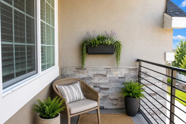Balcony featuring a stucco exterior, stacked stone accent wall, black horizontal railing, and a large multi-pane window. AI decor