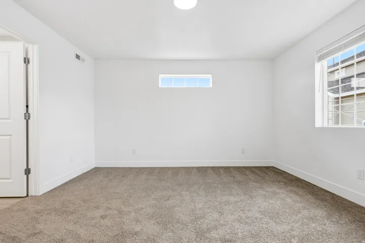 Spacious room featuring neutral carpet flooring, white walls, and a white ceiling with a flush-mount light fixture