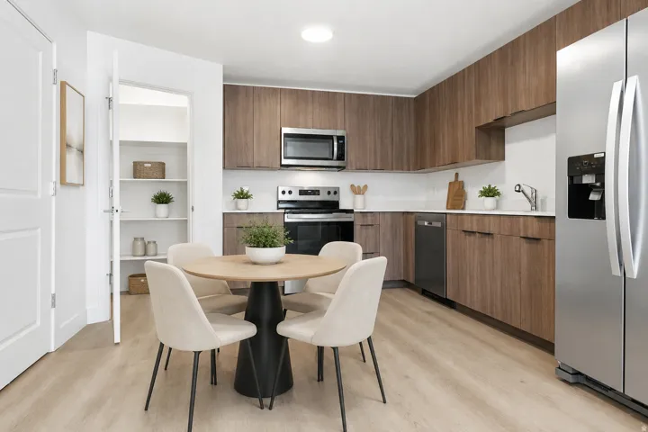 Contemporary kitchen featuring wood-finish cabinetry, stainless steel appliances, and light-toned flooring. AI Decor