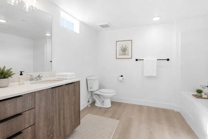 Bathroom featuring a modern vanity with wood-finish cabinetry and a light-toned countertop, a rectangular undermount sink, and a large mirror