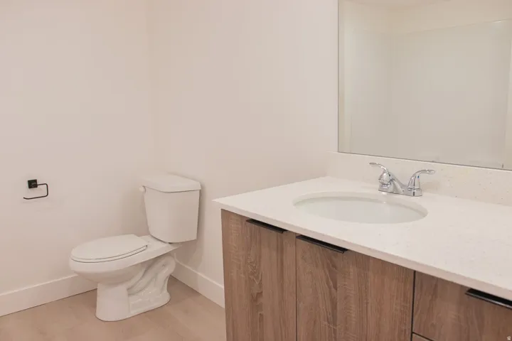 Vanity featuring a quartz countertop with an integrated sink, chrome faucet, and wood-finish cabinetry with dark hardware