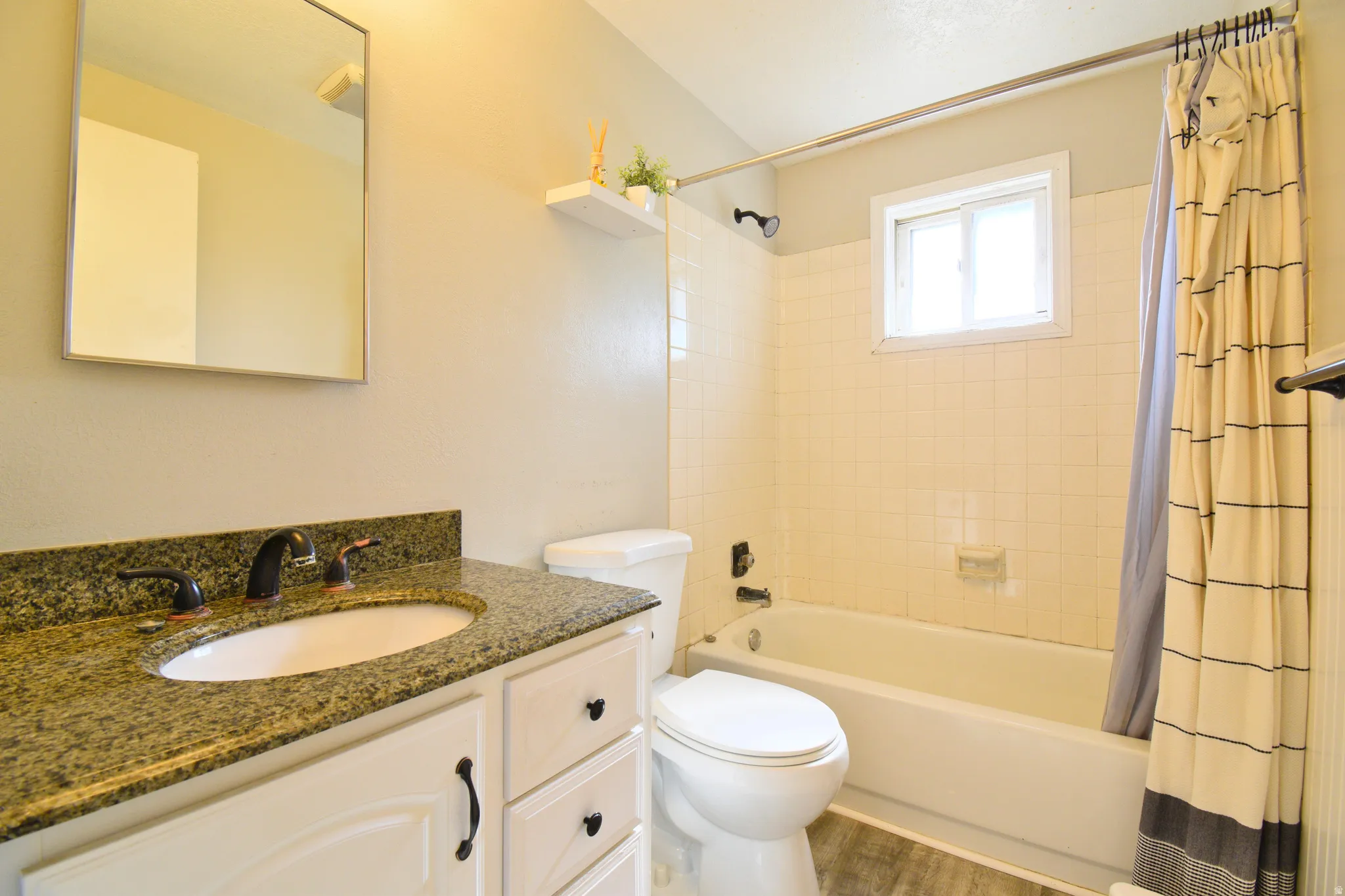 Bathroom featuring a white vanity with an undermount sink, granite-style countertop, and bronze-finish faucet