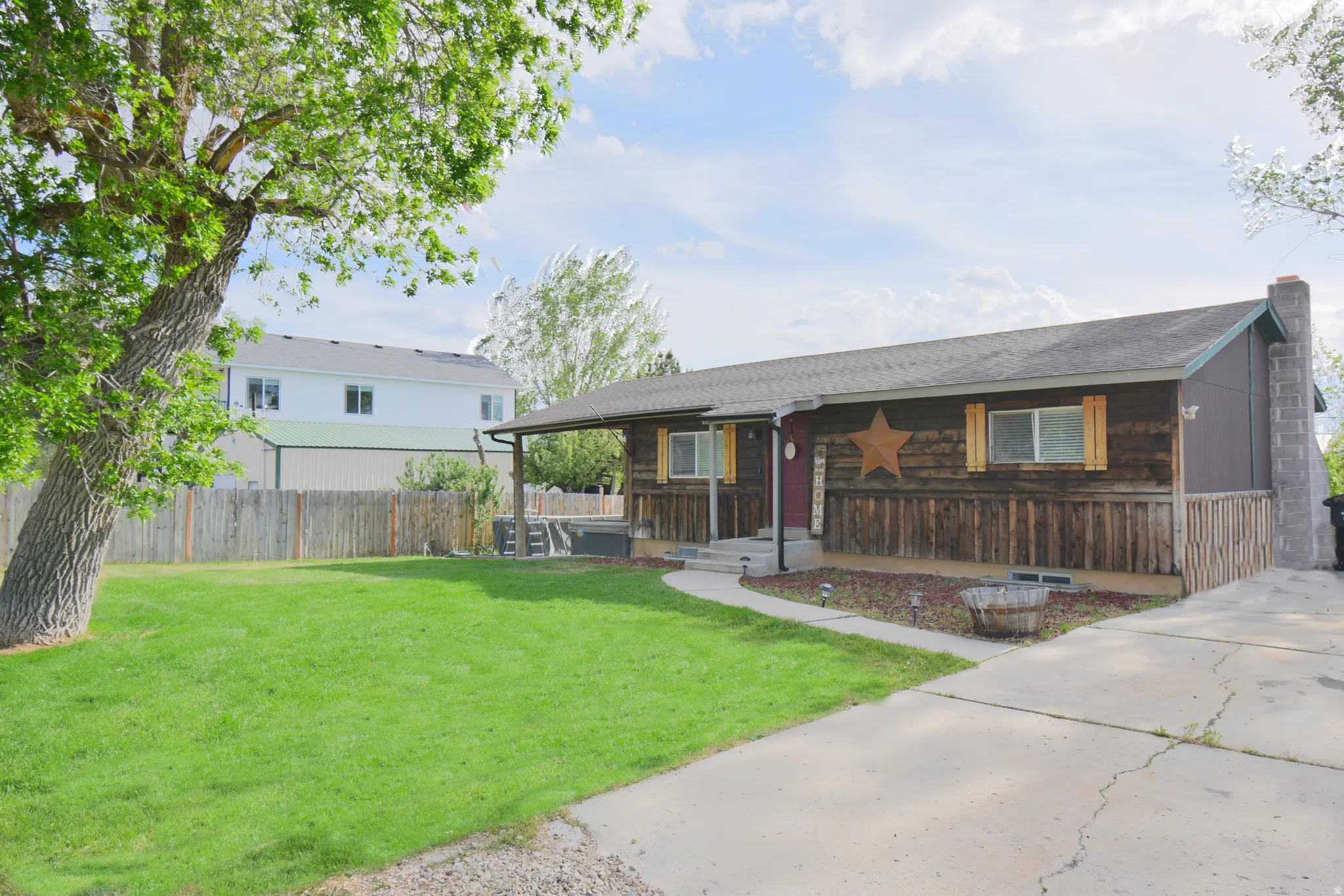 Ranch-style residence featuring a natural wood siding facade, a covered front porch, and a concrete driveway