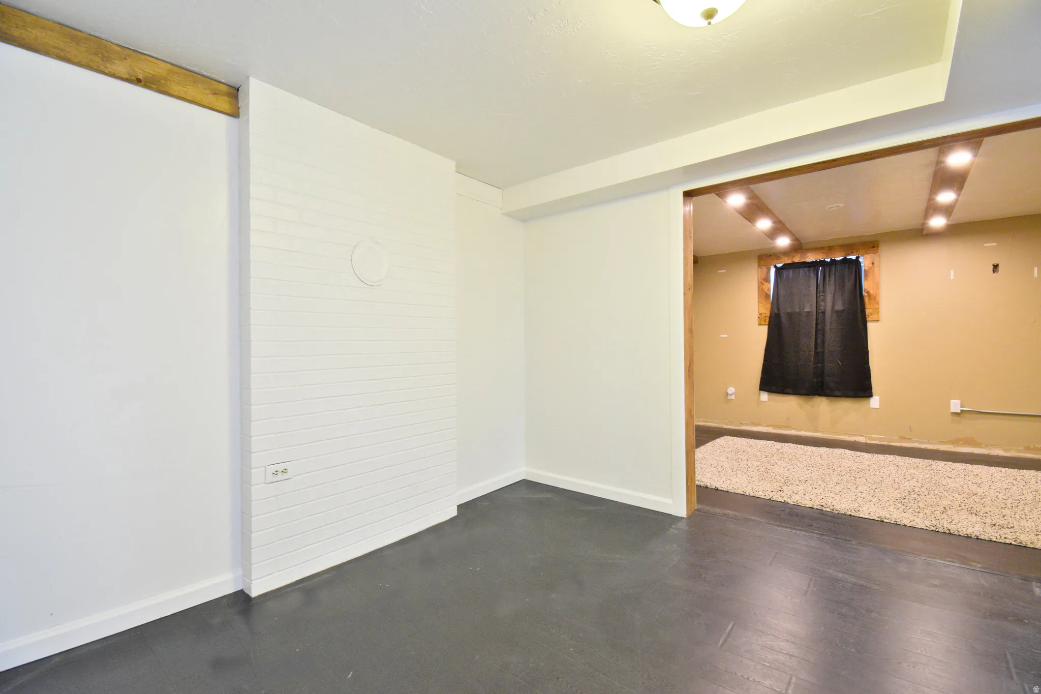 Bright interior space featuring a white painted brick accent wall, dark flooring, and a ceiling light fixture