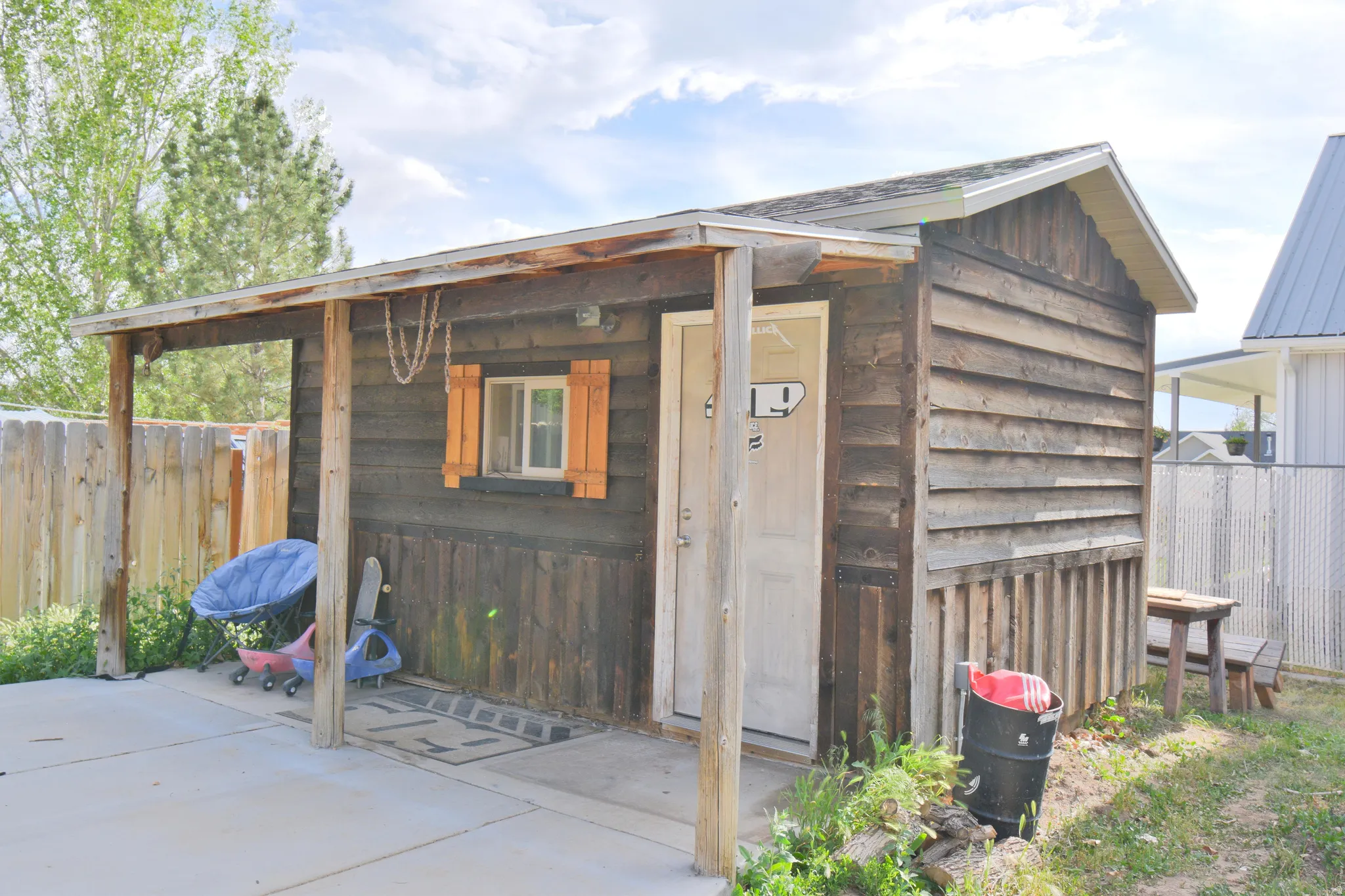 Rustic outbuilding featuring horizontal wood siding, a covered porch area, and a white entry door