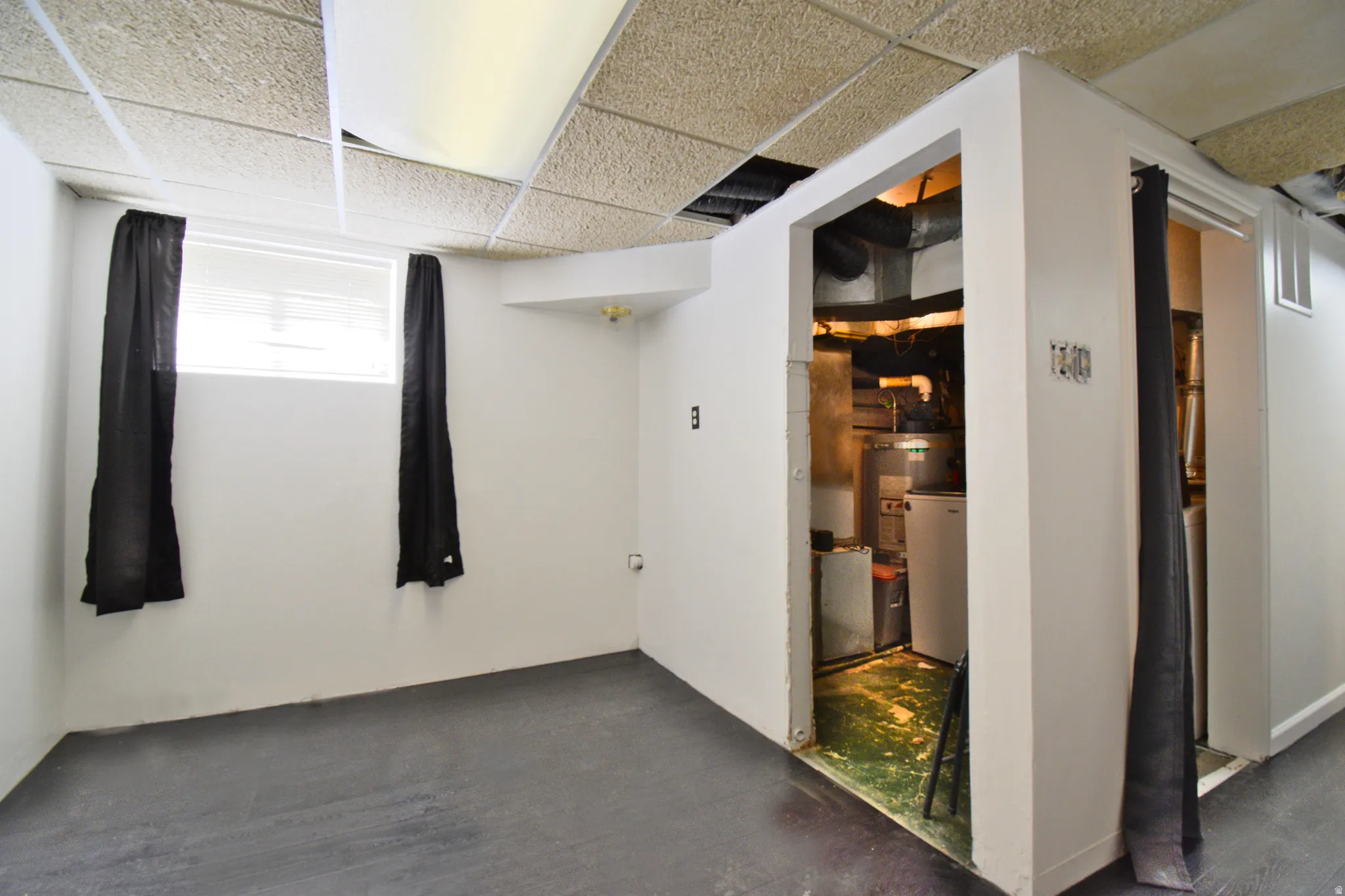 Finished room featuring dark flooring, white walls, and a drop ceiling