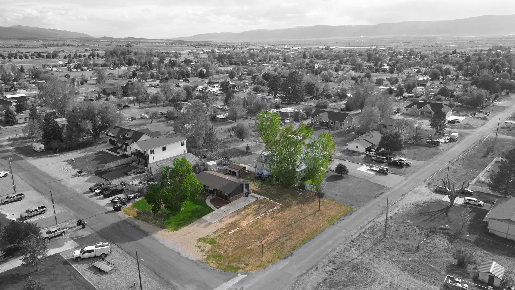 Aerial view showcasing a corner lot with an established residence featuring mature trees