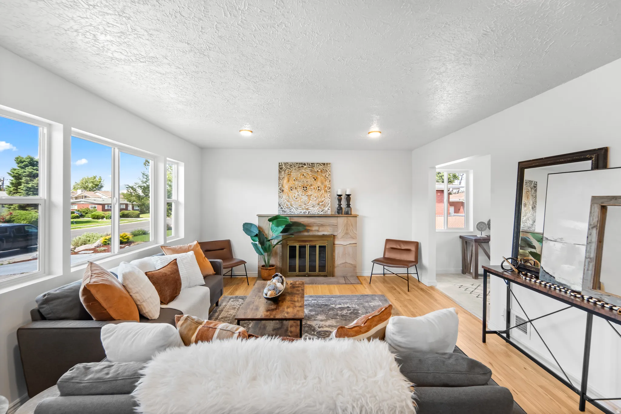 Living area featuring multiple windows, a fireplace with a stone surround, and wood-finish flooring