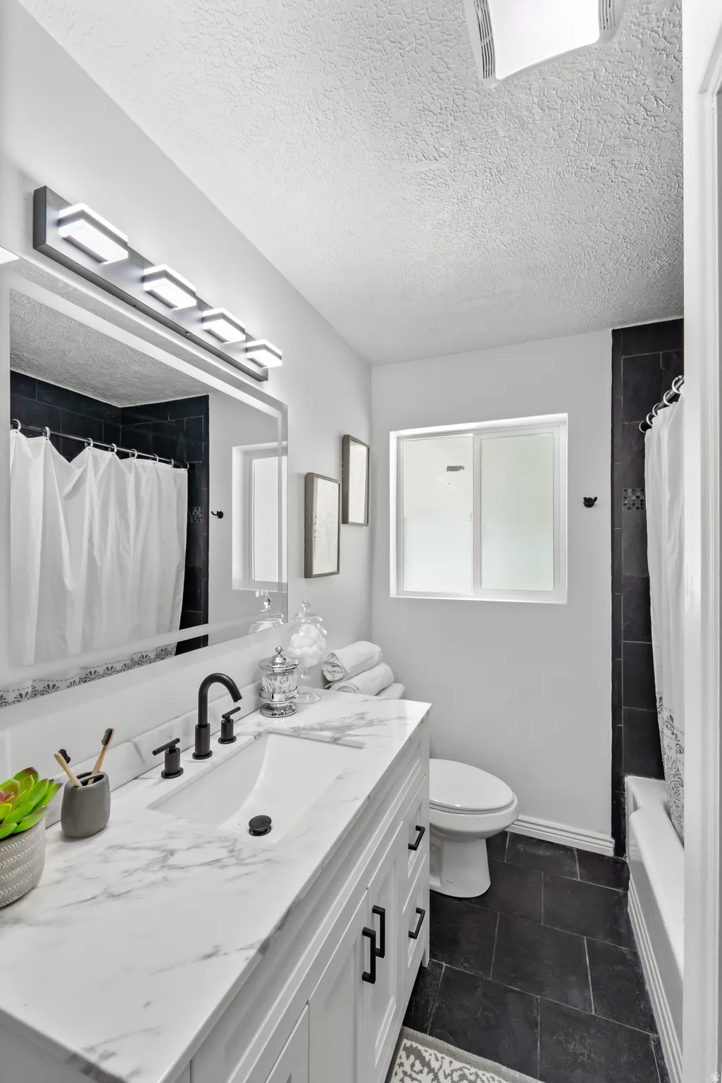 Bathroom featuring a white vanity with a marble-patterned countertop, an undermount sink, and matte black fixtures