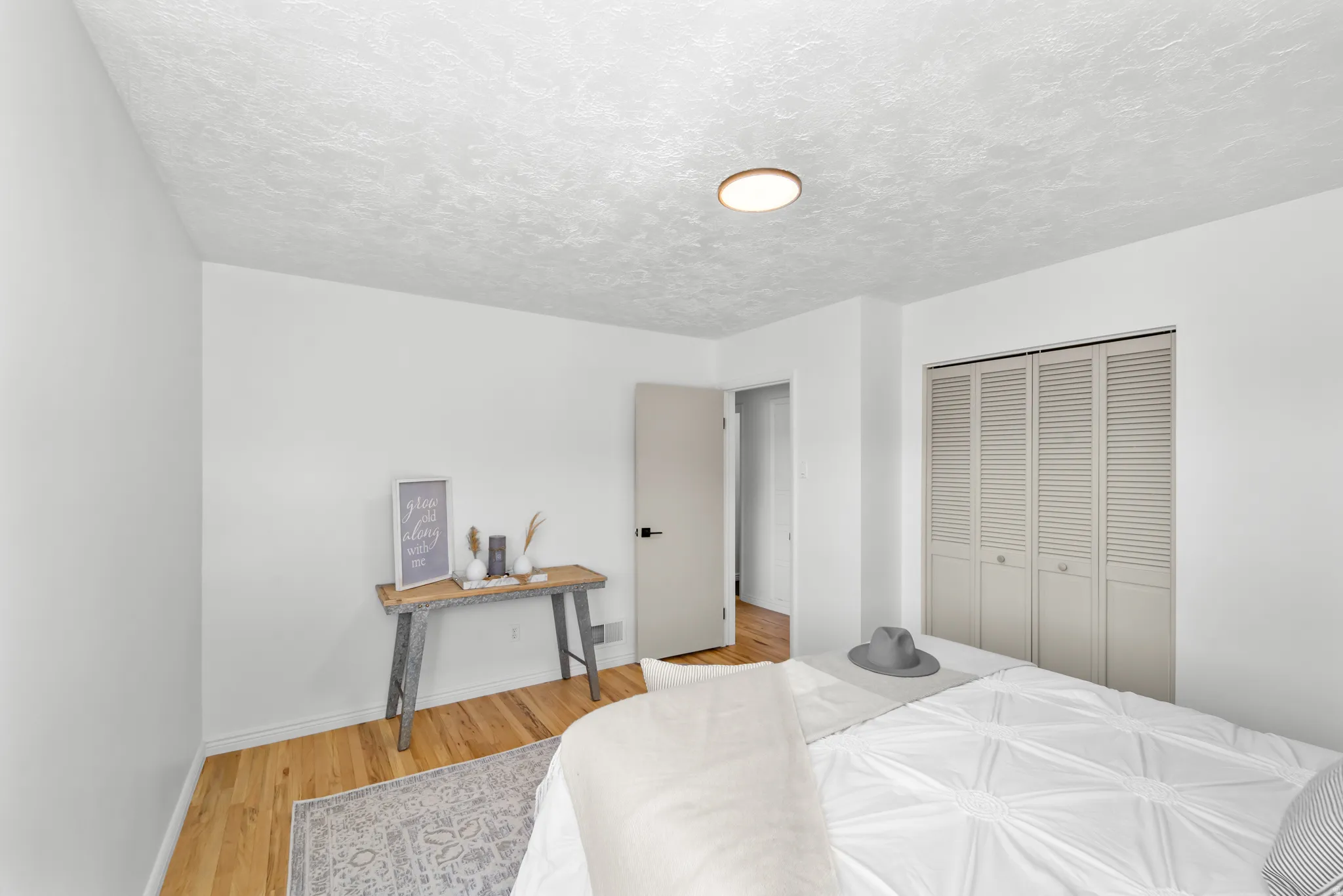 Bedroom featuring wood-finish flooring, white walls, and a built-in closet with louvered bi-fold doors
