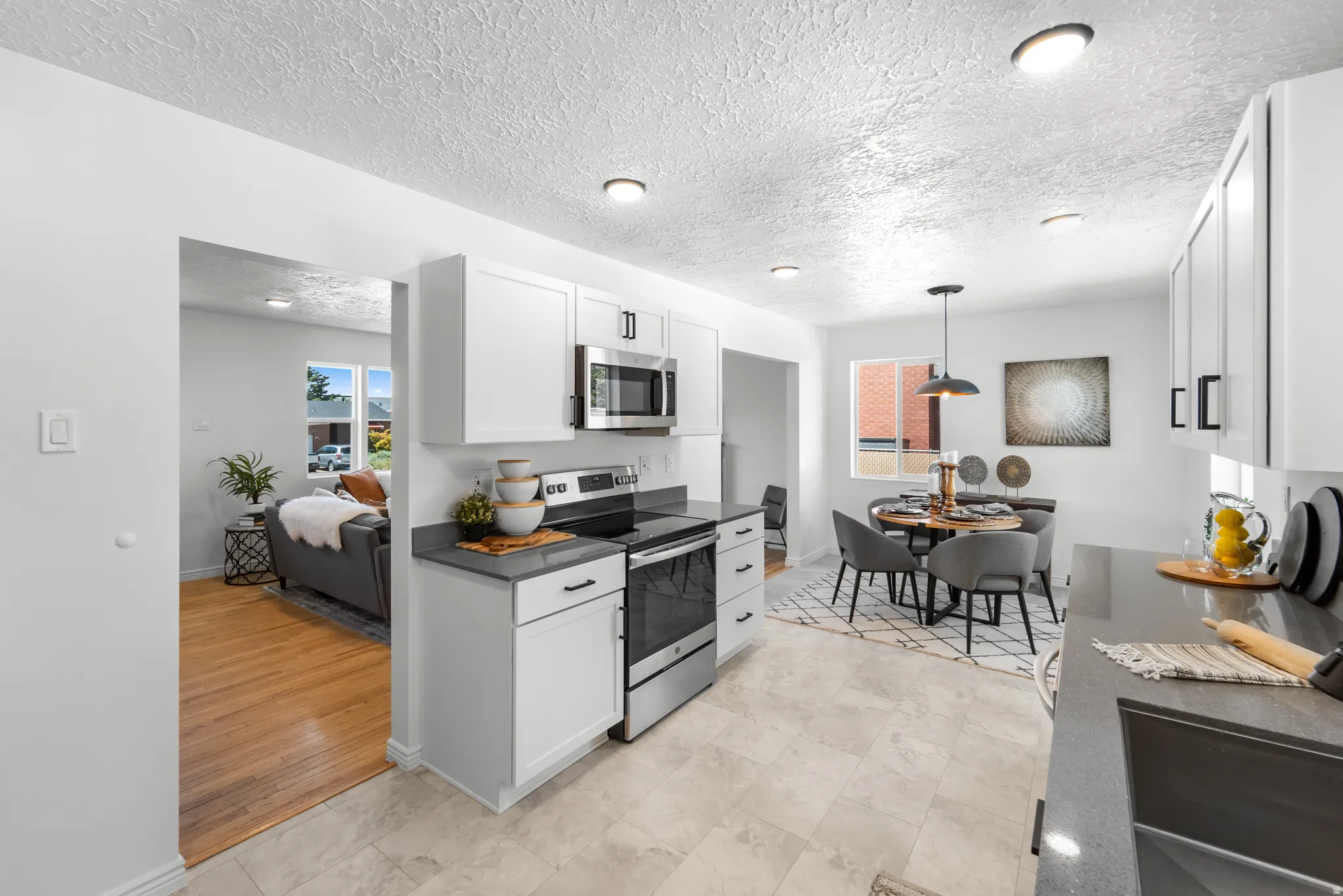 Modern kitchen featuring white cabinetry with dark hardware, stainless steel appliances, and grey countertops