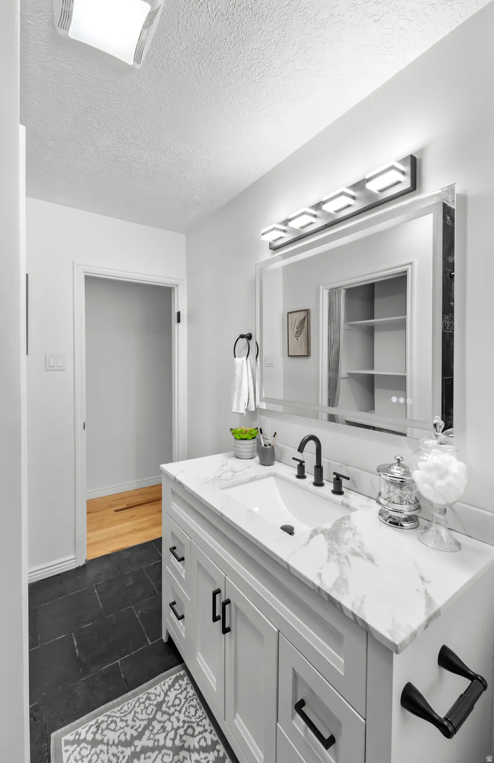 Bathroom vanity with a white marble-look countertop, integrated rectangular sink, and matte black faucet