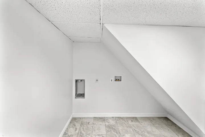 Utility room featuring neutral wall paint, a dropped ceiling, and tile flooring