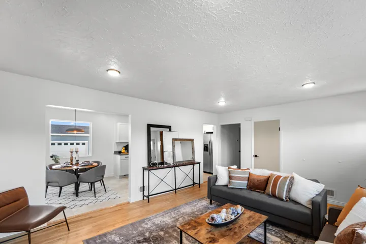 Spacious living area featuring wood-finish flooring, recessed lighting, and a white color palette