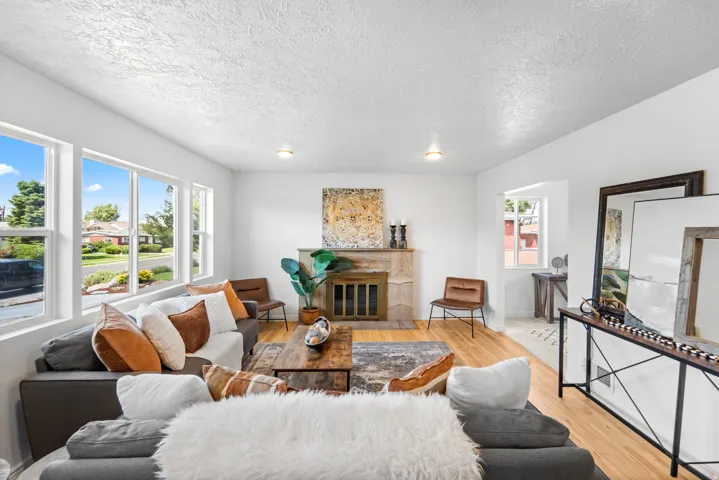 Living area featuring multiple windows, a fireplace with a stone surround, and wood-finish flooring