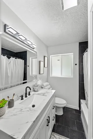 Bathroom featuring a white vanity with a marble-patterned countertop, an undermount sink, and matte black fixtures