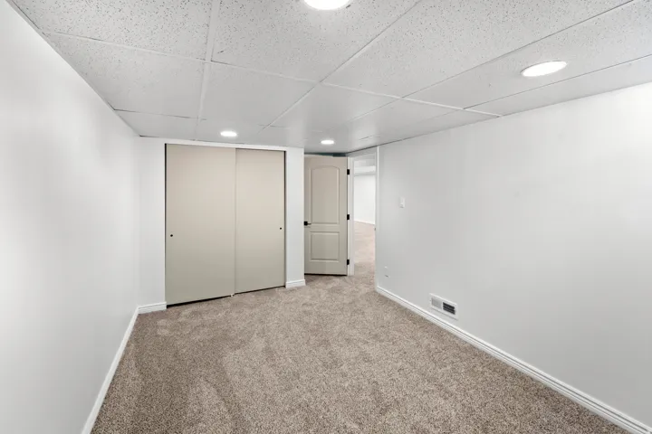 Carpeted room featuring white walls, recessed lighting, and a white acoustical tile ceiling