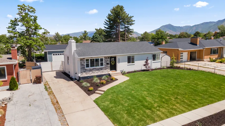Single-story residence featuring a gray shingled roof, stone veneer accents, and a light-colored exterior