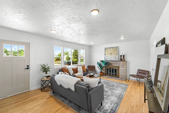 Living area featuring wood-finish flooring, a stone fireplace, recessed lighting, and multiple windows