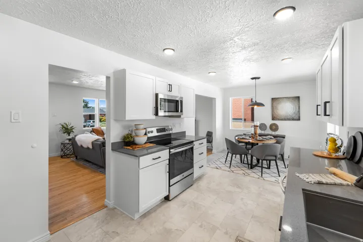 Modern kitchen featuring white cabinetry with dark hardware, stainless steel appliances, and grey countertops