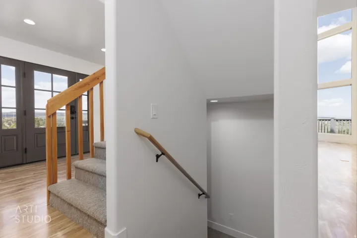 Carpeted staircase featuring a natural wood banister and handrail