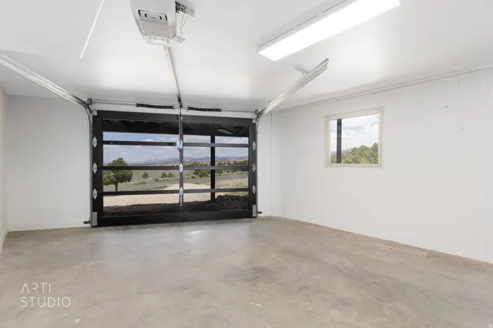 Spacious garage featuring a full-glass overhead door, concrete flooring, and a single window for natural illumination
