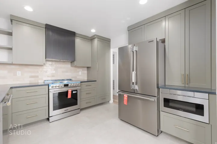 Contemporary kitchen featuring recessed lighting, light gray cabinetry, stainless steel appliances, a textured tile backsplash, and dark countertops
