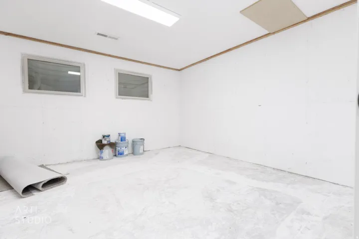 Spacious unfinished room featuring two horizontal windows, white walls, and a concrete floor