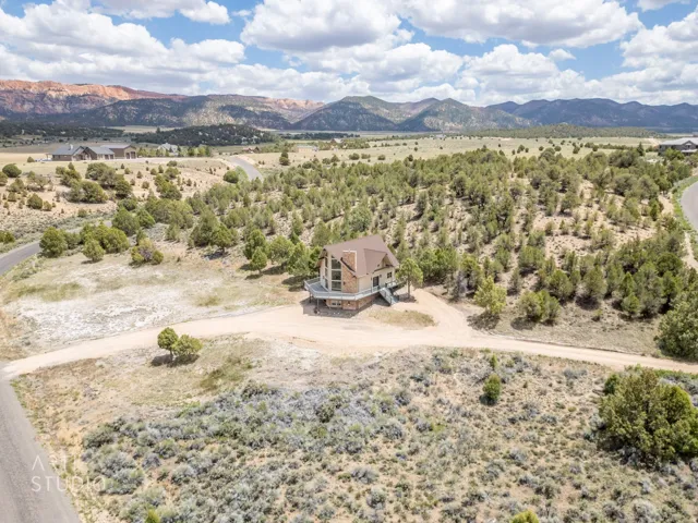 Property with a light brown exterior and a dark brown roof, surrounded by natural desert landscaping and scattered trees