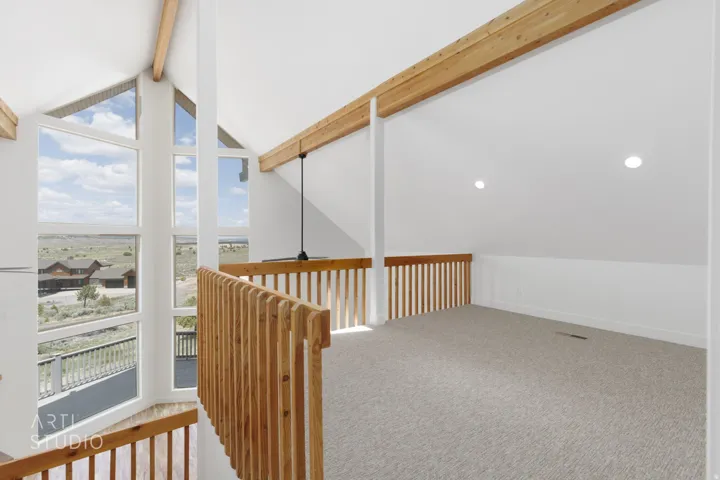 Loft space featuring abundant natural light, vaulted ceilings with exposed wood beams, neutral carpeting, recessed lighting, and wooden railing