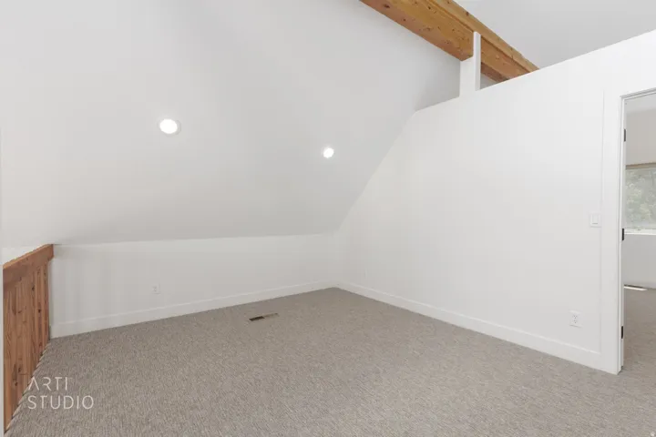 Open loft space featuring vaulted ceilings, exposed wood beams, recessed lighting, and light-colored carpeting