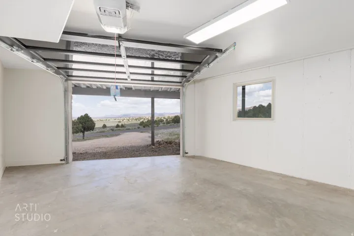 Attached garage featuring a concrete floor, white panel walls, and a window for natural light