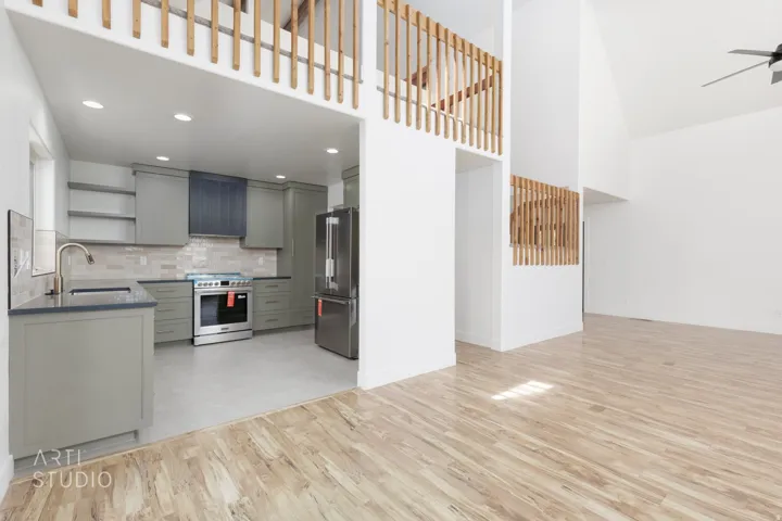 Open concept living space featuring wood-finish flooring, a vaulted ceiling, and a modern ceiling fan