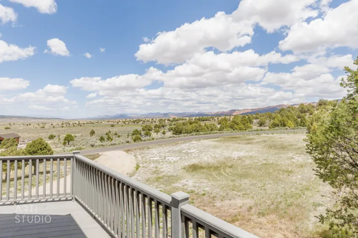 Outdoor deck with gray railing overlooking a vast landscape featuring natural vegetation and distant mountains