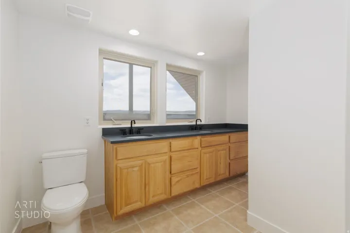 Dual-sink vanity with wood-finish cabinetry and a dark countertop