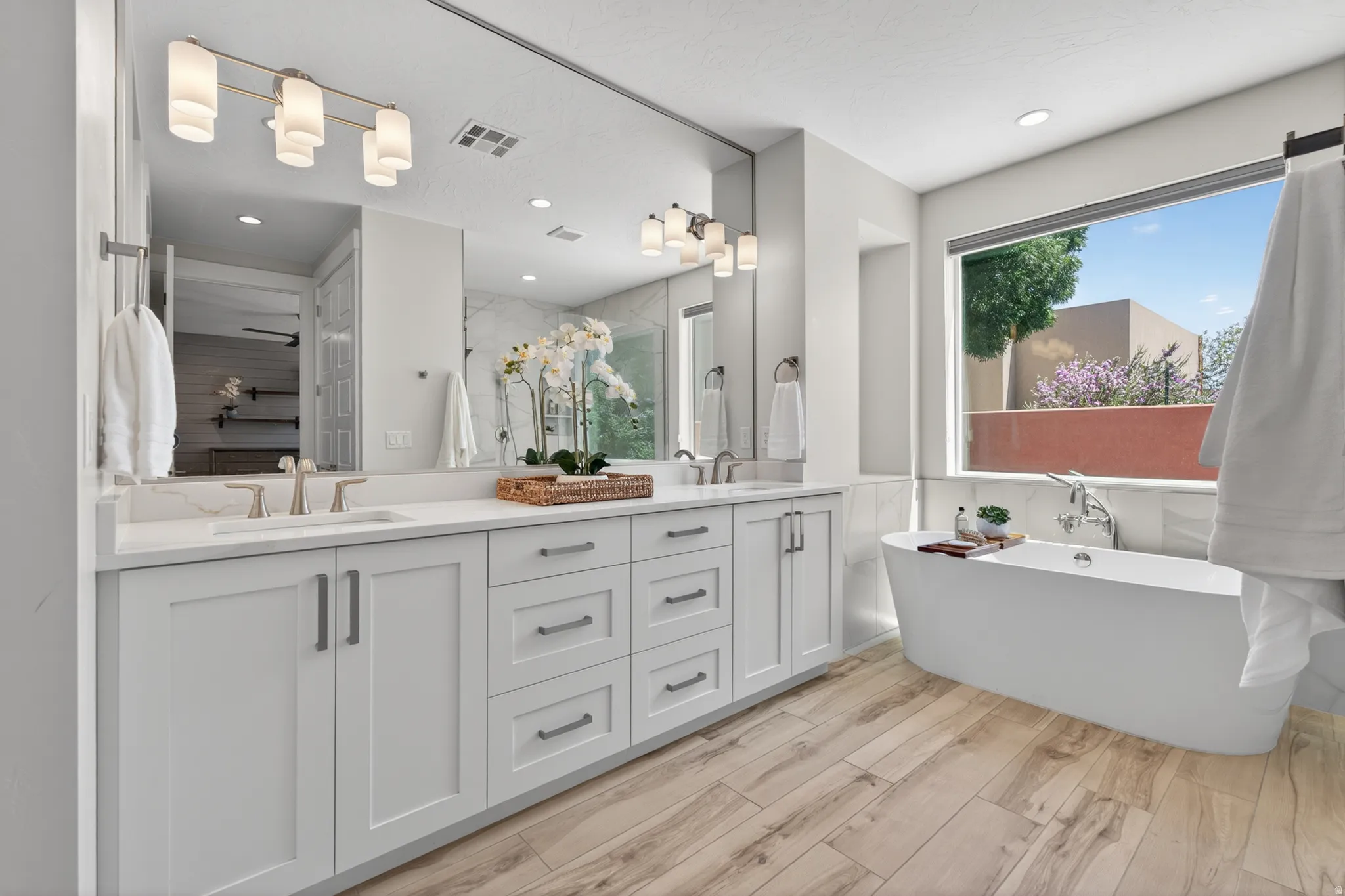 Spacious bathroom featuring a dual vanity with white cabinetry, light-toned countertops, and dual undermount sinks