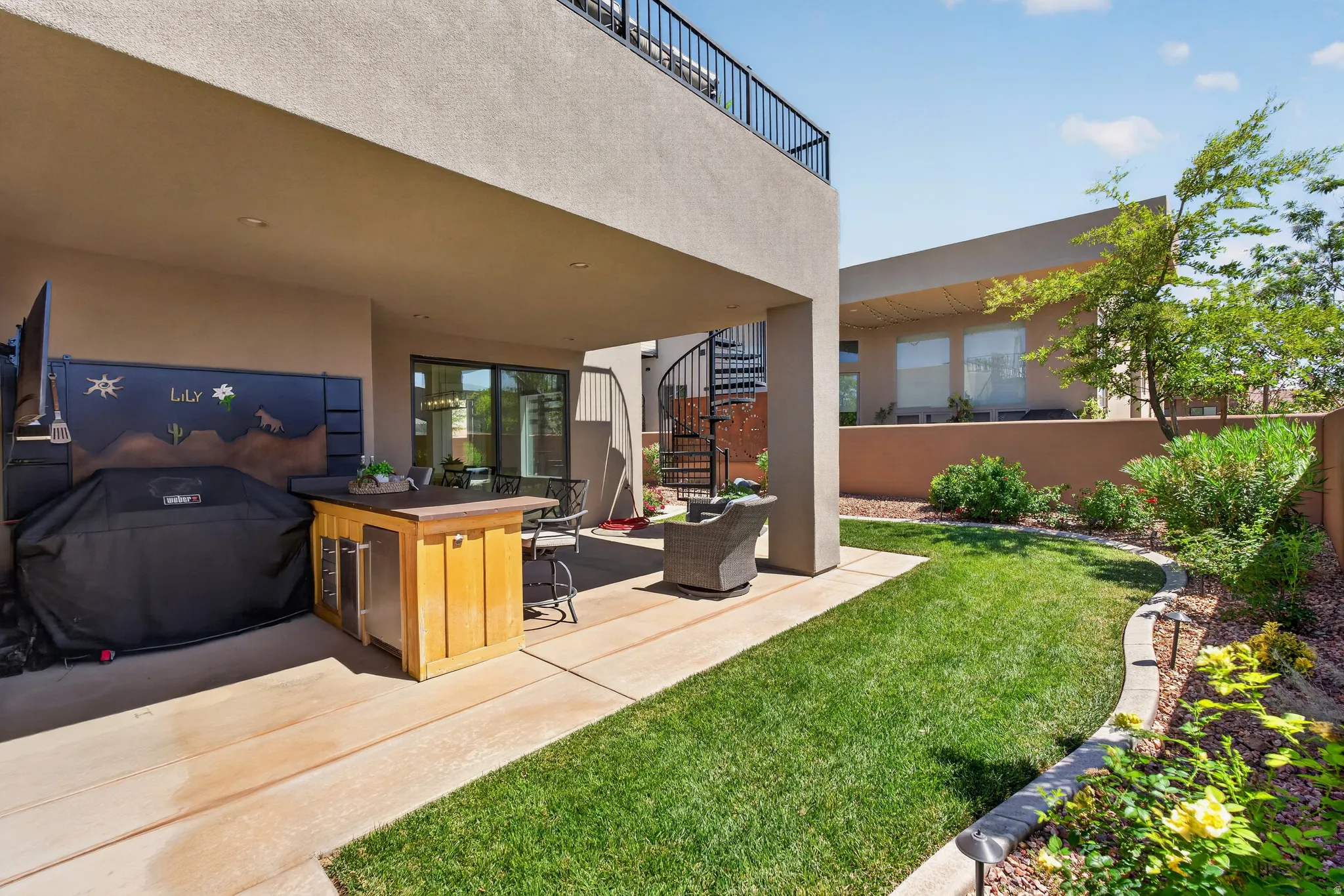 Covered patio featuring an outdoor bar with built-in beverage refrigerator, a spiral staircase, and an upper-level balcony