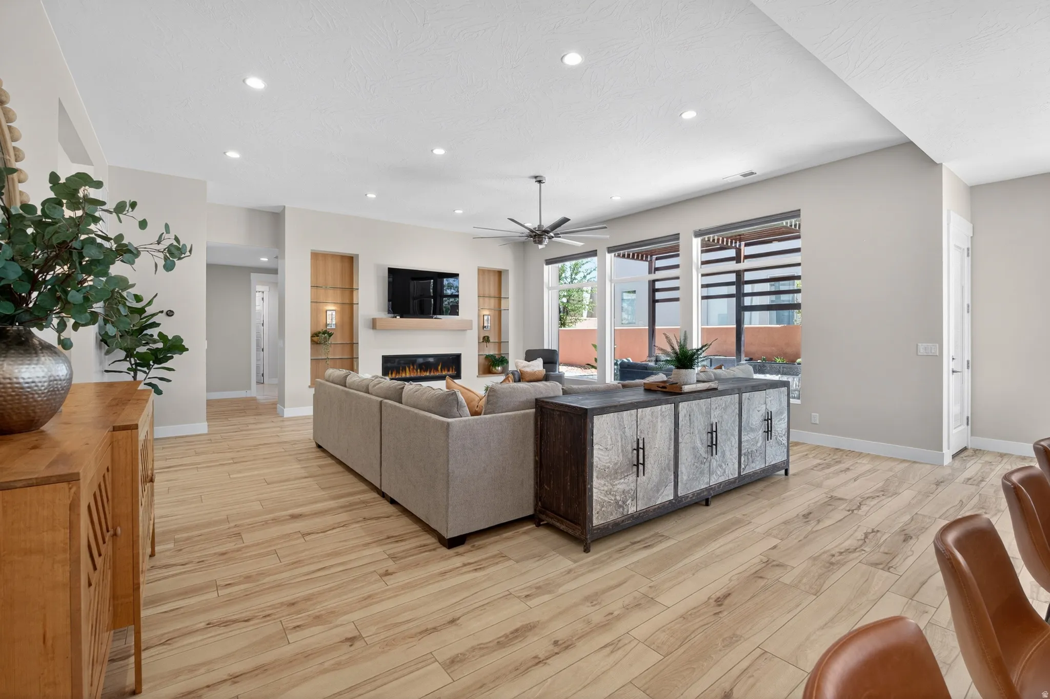 Spacious living area featuring wood-finish flooring, recessed lighting, and a contemporary fireplace with a wood mantle