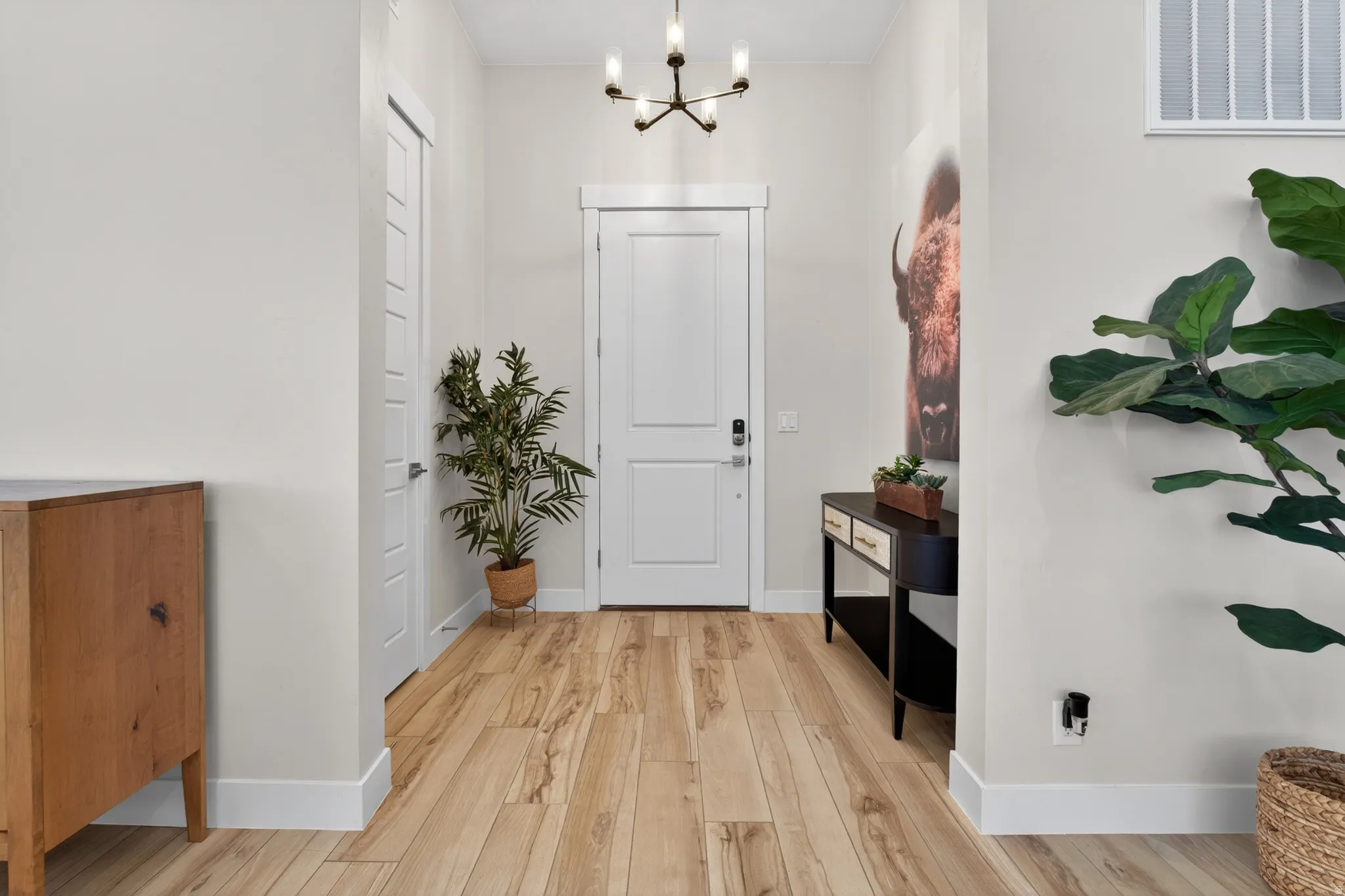 Bright entryway featuring light wood-finish flooring and a contemporary chandelier