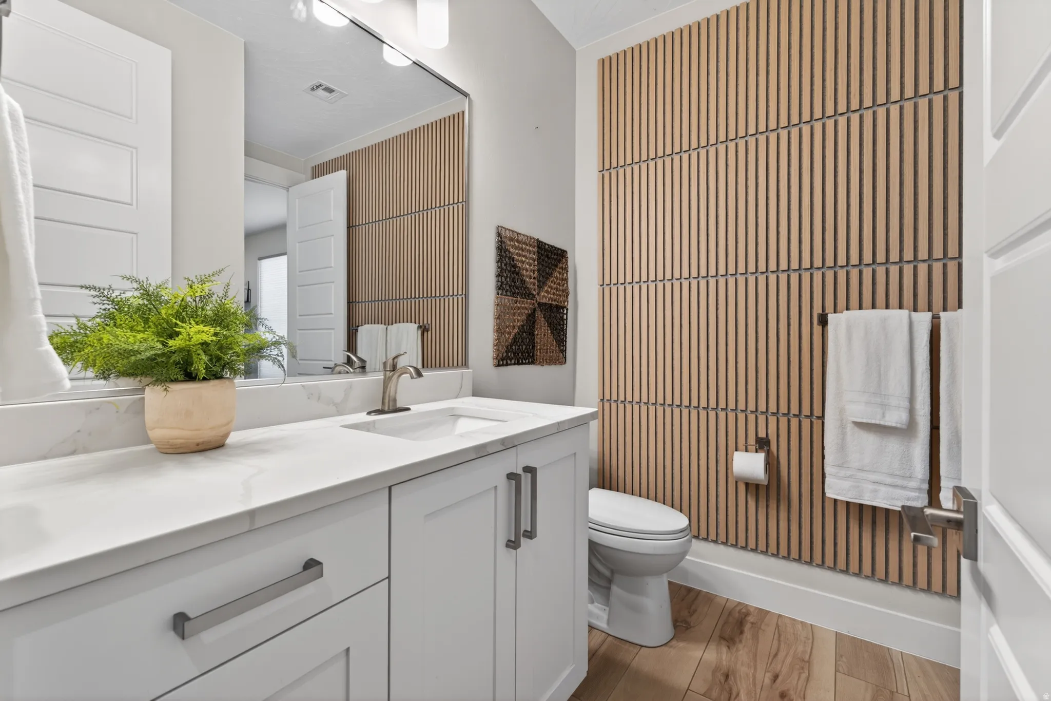 Bathroom featuring a contemporary vanity with a white countertop and undermount sink, brushed nickel faucet, and integrated storage cabinetry