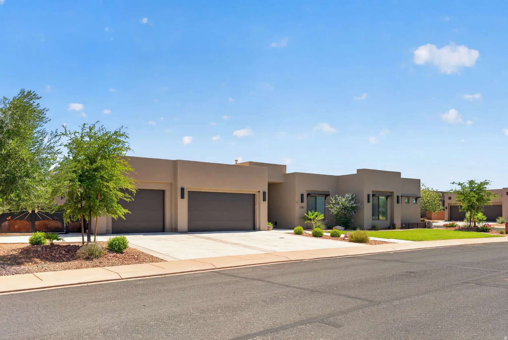 Contemporary stucco exterior with multiple garage bays, concrete driveways, and xeriscaped landscaping