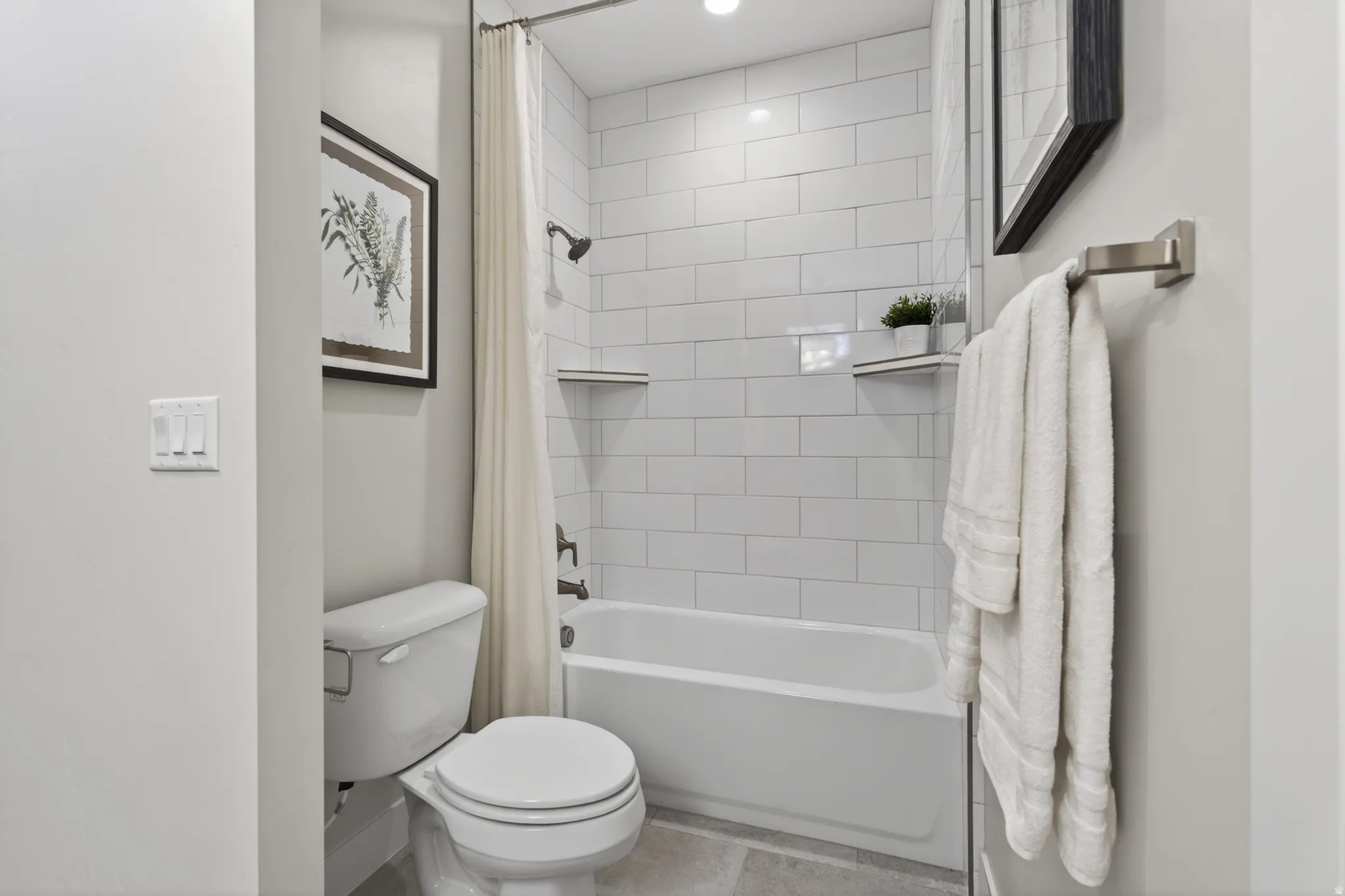 Bathroom featuring a white subway tile shower surround with integrated shelving, a built-in bathtub, and dark bronze bath fixtures