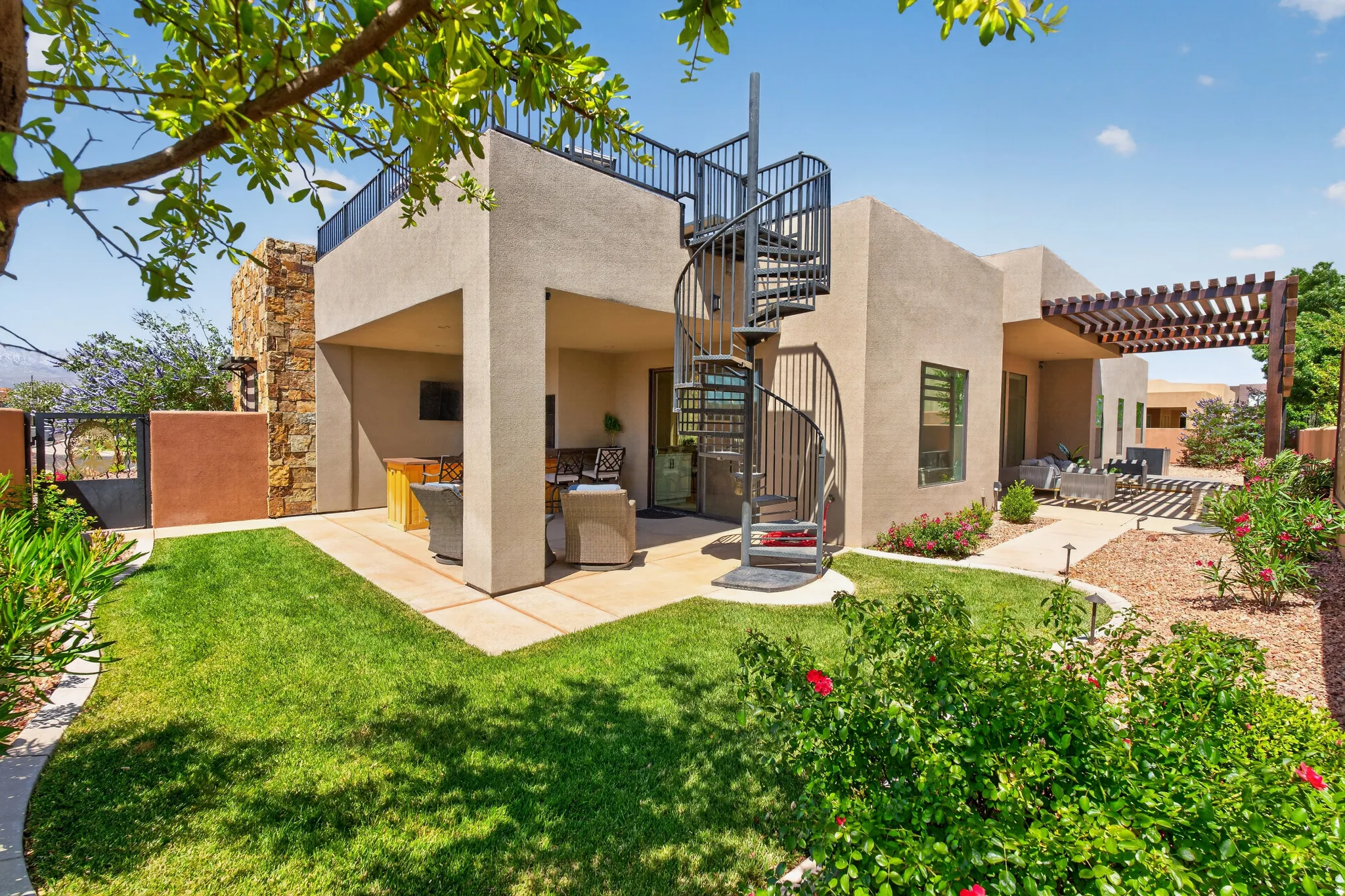 Expansive patio area featuring a metal spiral staircase leading to a rooftop deck with black railing